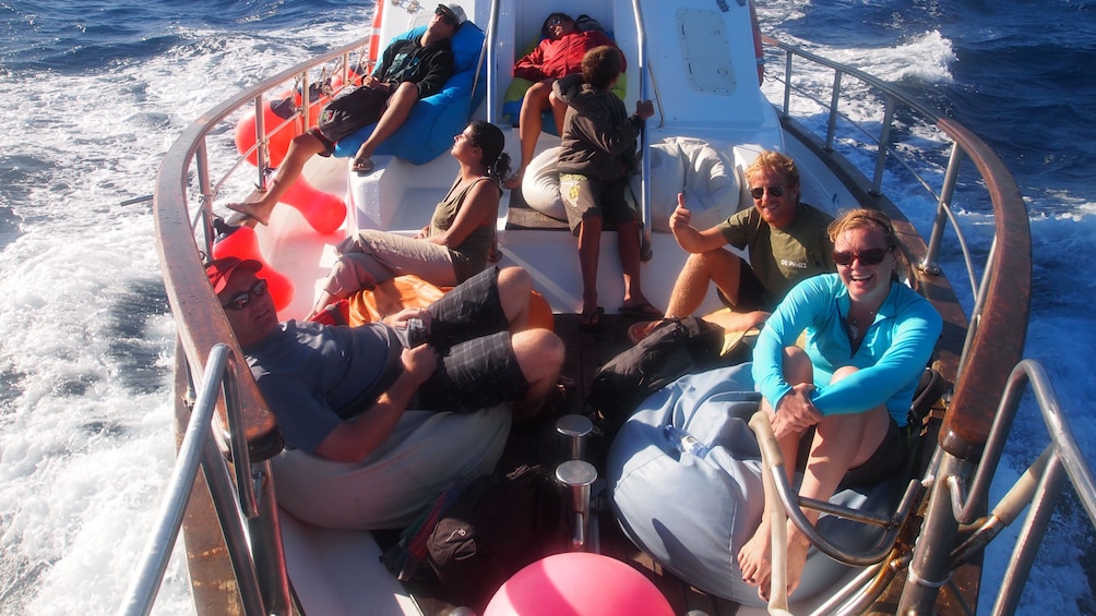 People sit on the bow of a boat off the coast of Lisbon