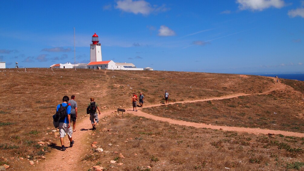 People walking on a path towards a lighthouse on Berlengas Islands