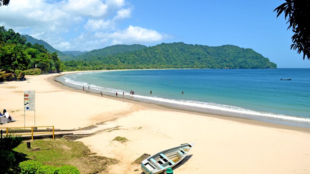 People wading in water along beach in Trinidad and Tobago