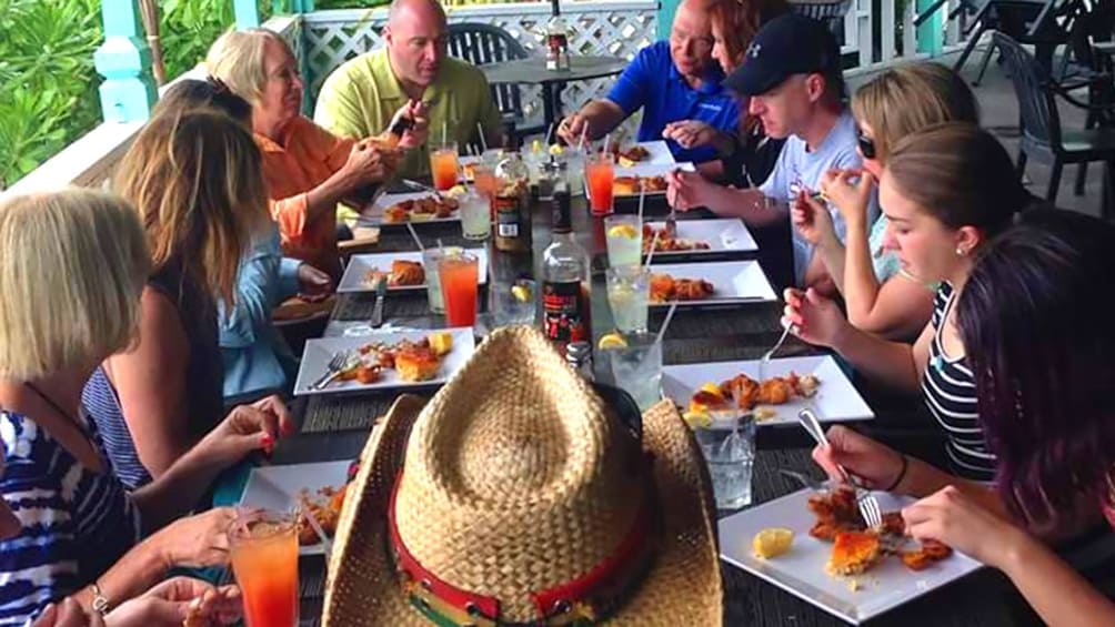 A table of people eating Caribbean food. 