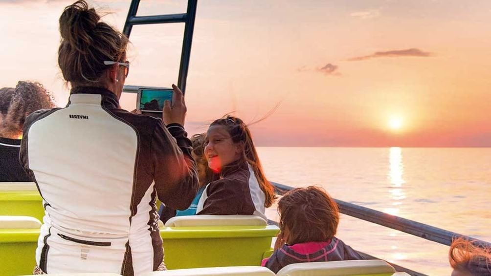 Woman taking picture at sunset on a boat