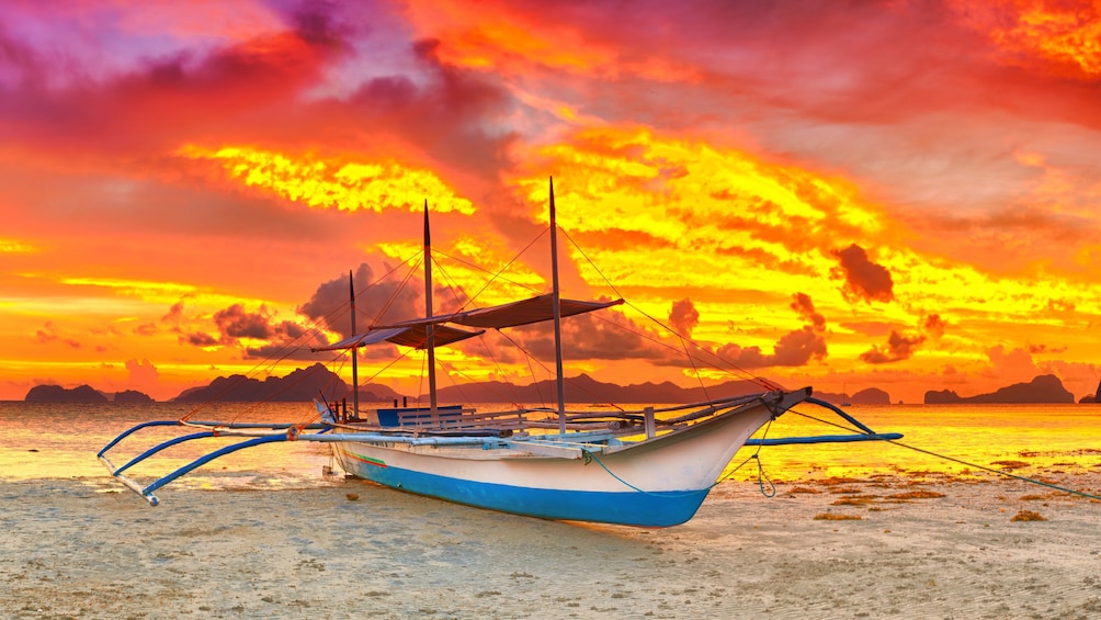 Boat on beach with dramatic sunset in background