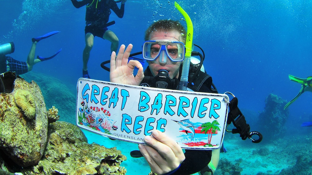 Snorkeler holding a Great Barrier Reef sign