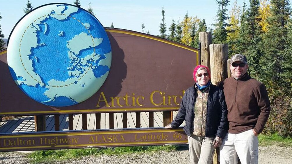 Couple at the sign for the Arctic Circle in Alaska