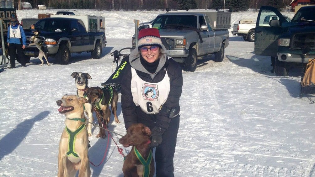 Woman petting dogs tethered to a sled in Alaska