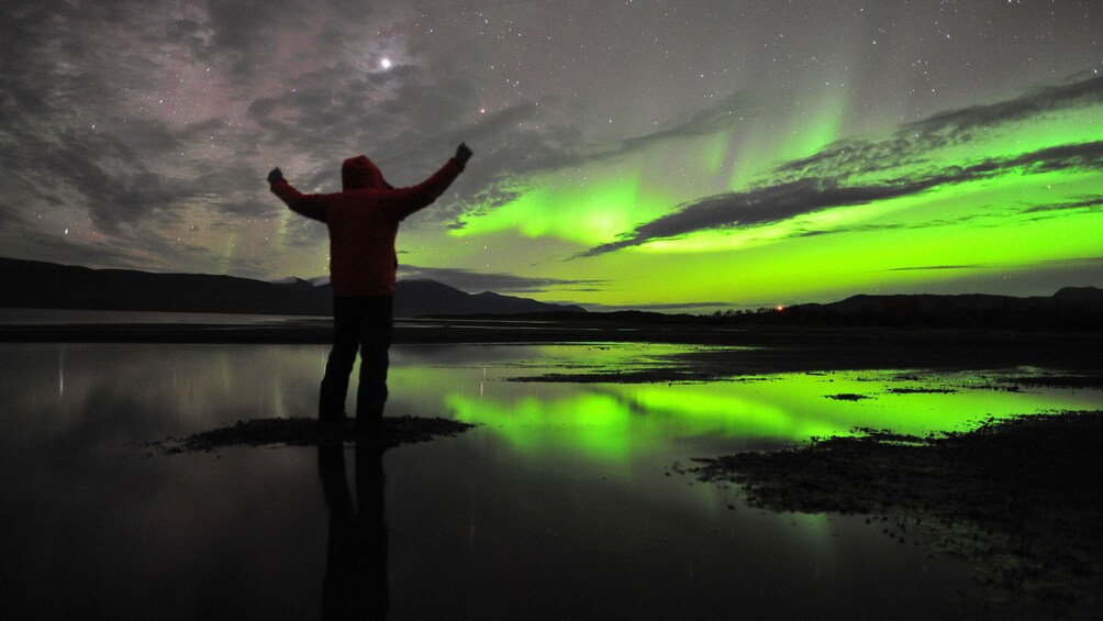 Åpne bilde 1 av 5. Silhouette of a person on the edge of a lake with Northern Lights glowing green in the sky in Stockholm