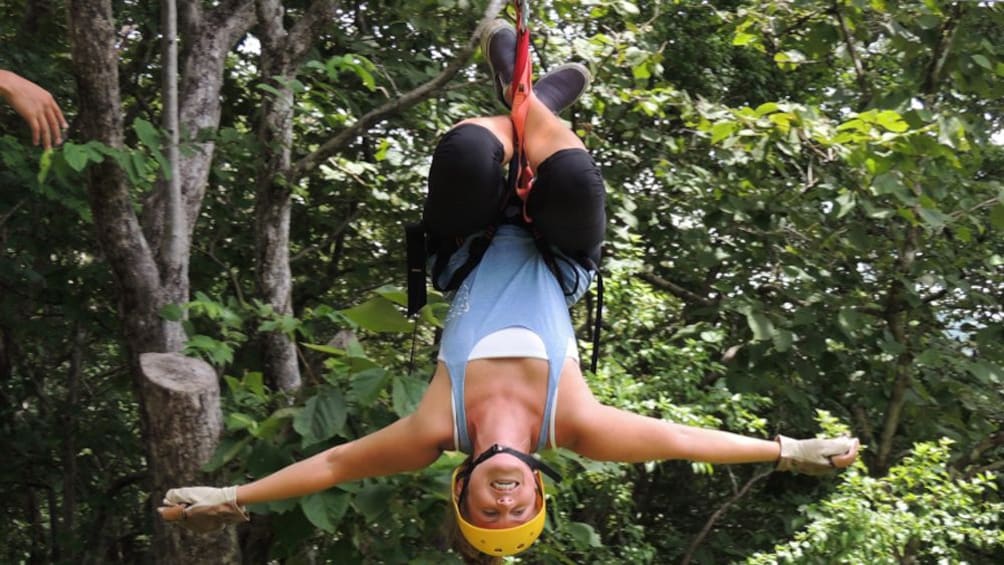 Woman hangs upside down on a zip line