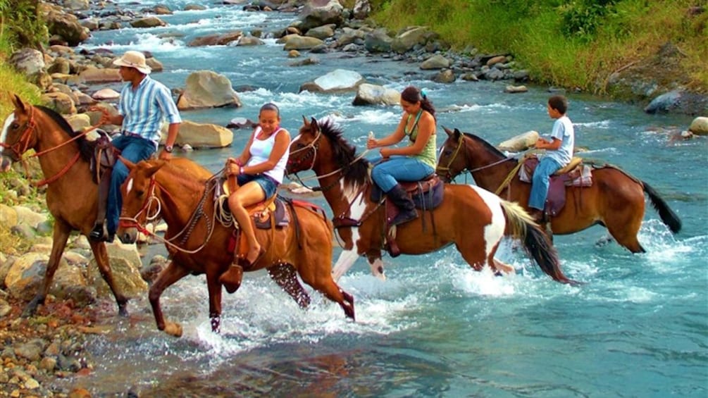 Group riding horseback through a river in Costa rica