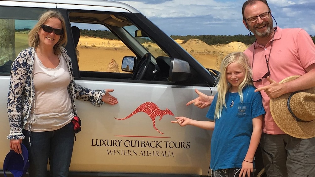 family posing with vehicle