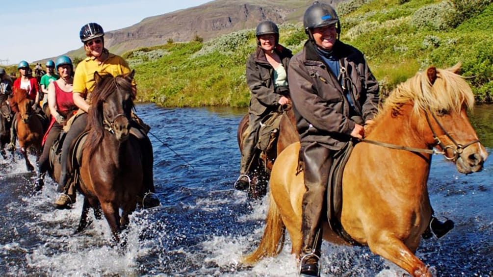People riding horseback in a stream