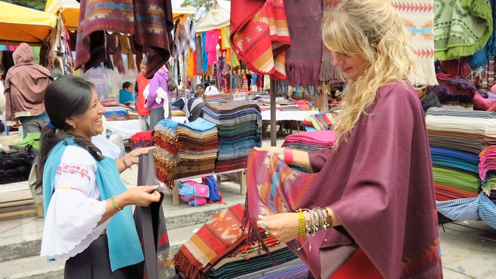 Woman buying fabric on the 	Otavalo Market Full Day Tour