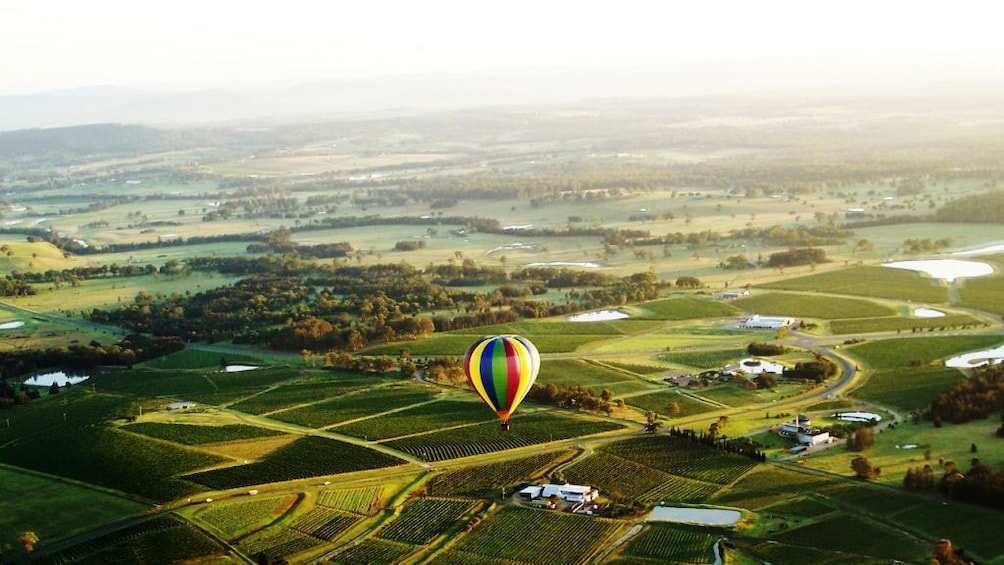 a hot air balloon floating high above landscape in Hunter Valley
