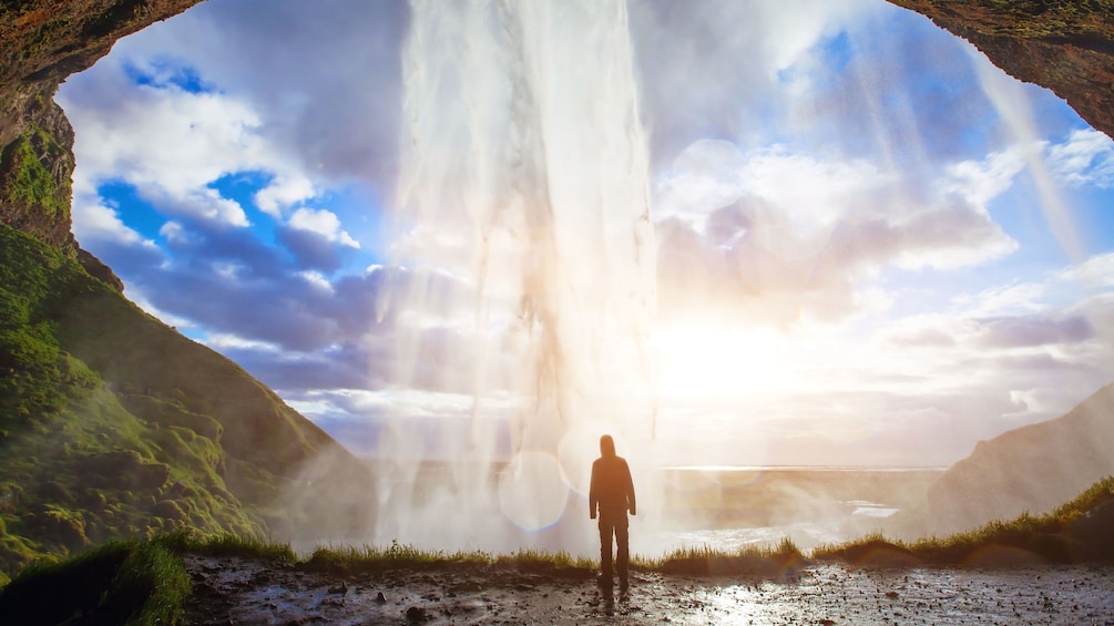 Man standing behind a waterfall in Reykjavik