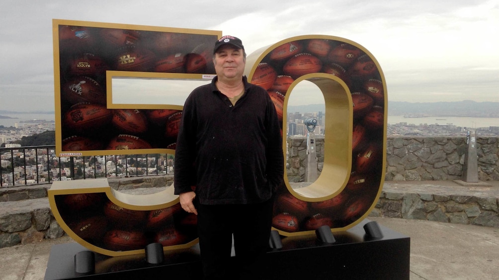 Man in front of the super bowl 50 sign in San Francisco 