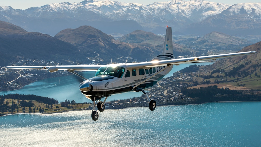 Plane flying over mountains and river of New Zealand