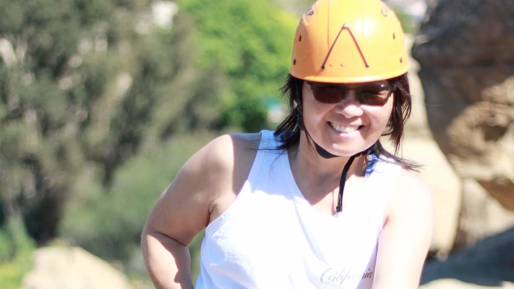 Show item 3 of 4. Woman wearing a safety helmet and smiling on the Rappelling Adventure at Joshua Tree