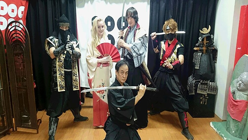 Show item 1 of 9. People posing in traditional Japanese clothing for photograph with swords in Osaka