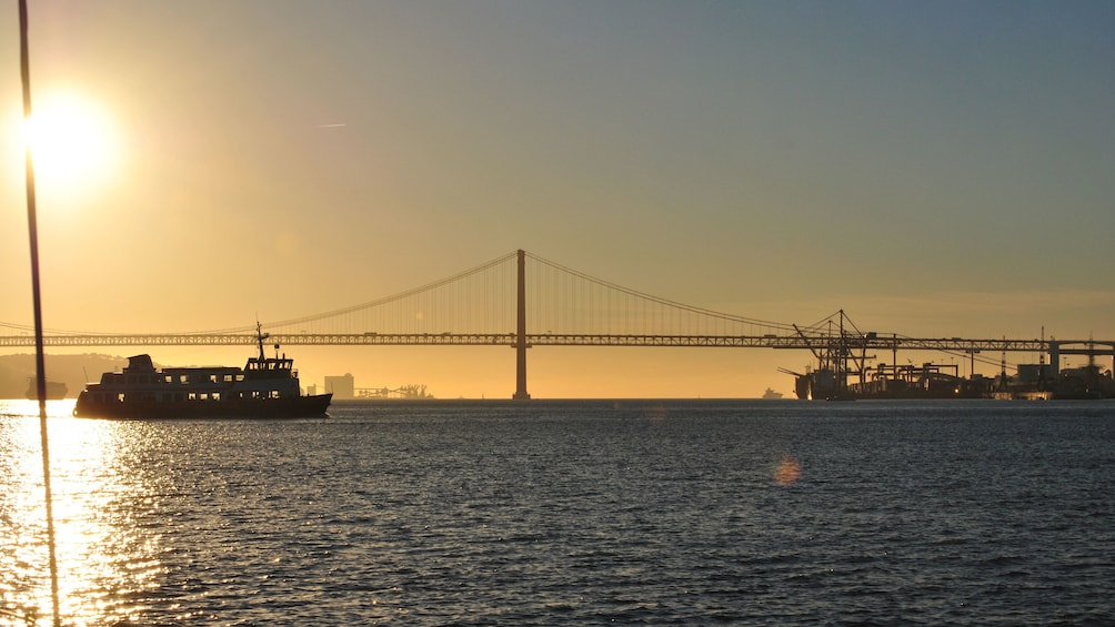 View of bridge and ferry in Lisbon at sunset