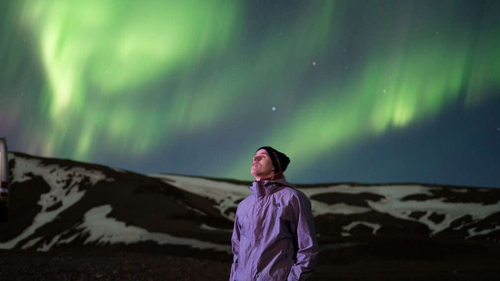 Man looking up at the Northern Lights in Reykjavik