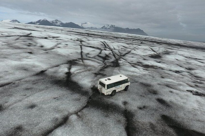 A Blue Iceland glacier vehicle (Unimog) upon the glacier, snapped with a drone.