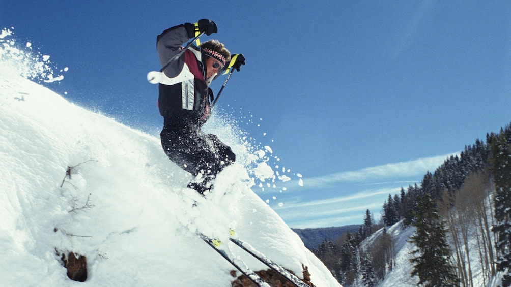 Skier goes off a jump on a mountain