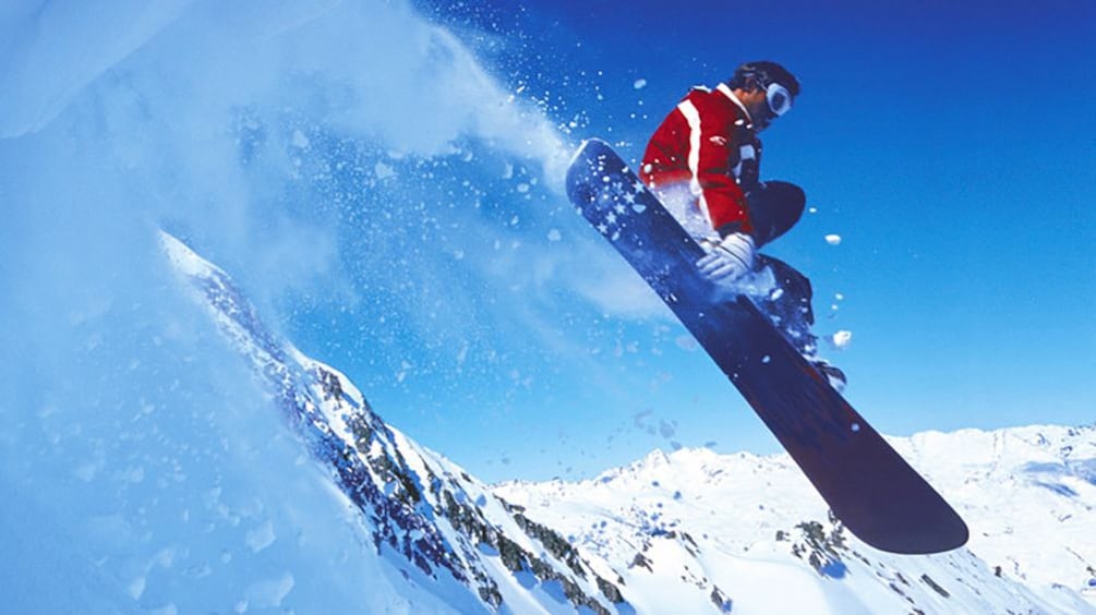 Snowboarder riding off a jump on a mountain top