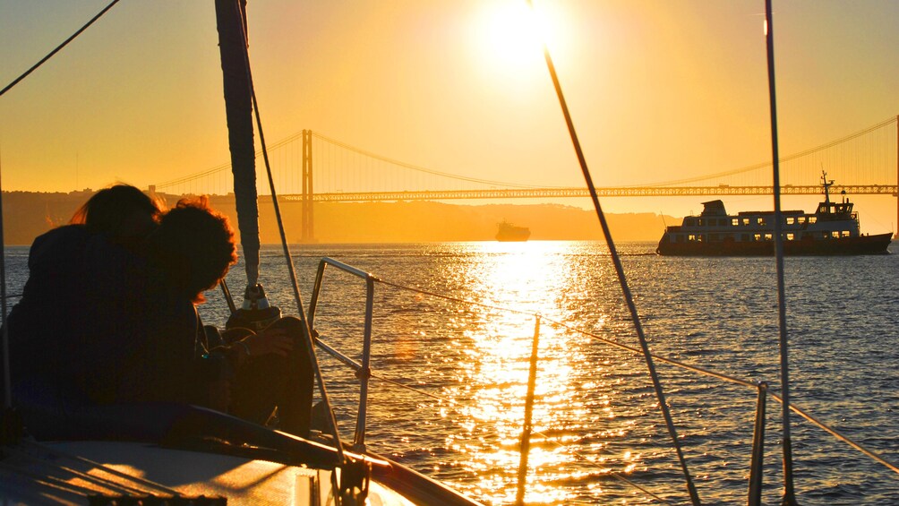 People on the bow of a sailboat at dusk