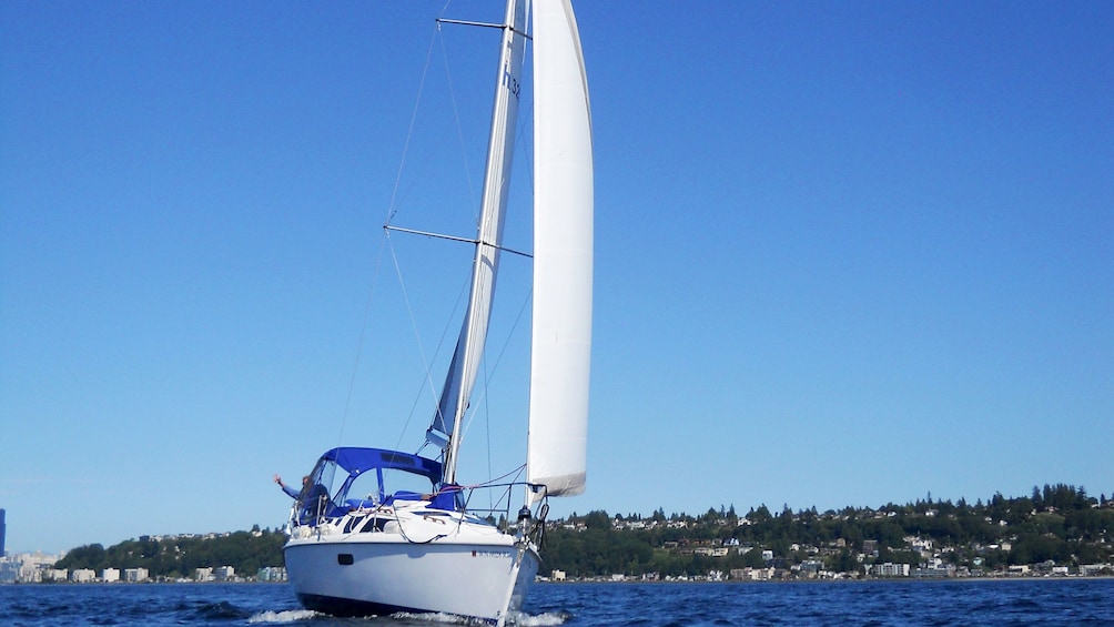 Sailboat with wind in sails moving though the water of Puget Sound