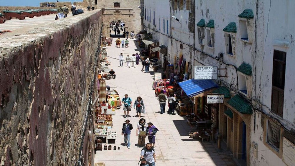 Tourist walking through the street with street vendors along the walls in Essaouira