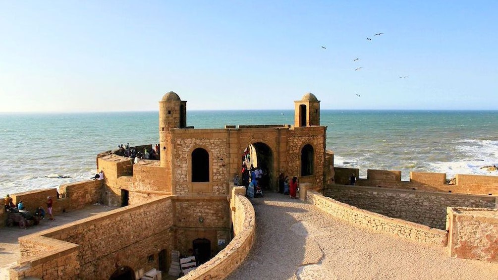 Tourist looking through fort near the ocean in Essaouira