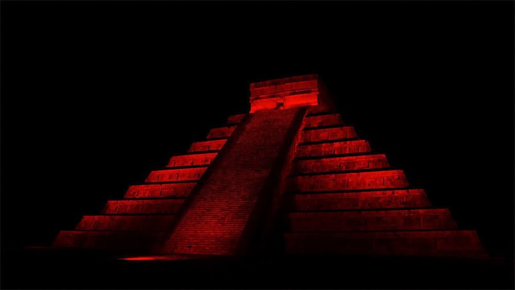 Colored lights projected onto the Chichen Itza temple at night in Cancun