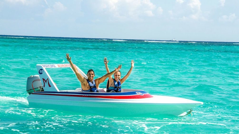 Couple with arms up enjoying riding around in boat in Cancun