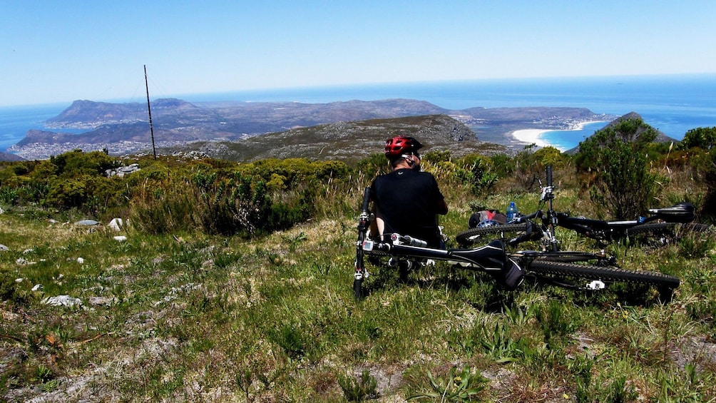 Mountain biker taking break on mountain looking over wide view on Table Mountain