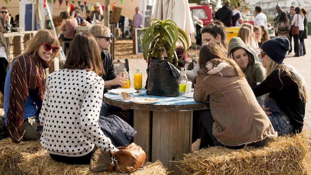 Group eating at a table with haystack benches at a market in Cape Town