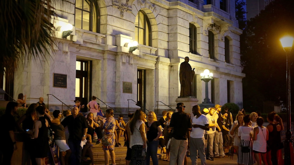 Tourist waiting outside building at night for tour to start in New Orleans