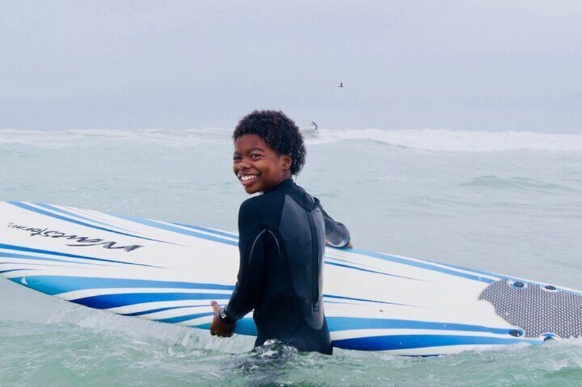 Boy smiles with his surfboard