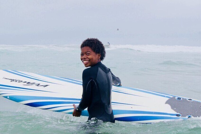 Boy grins with his surfboard