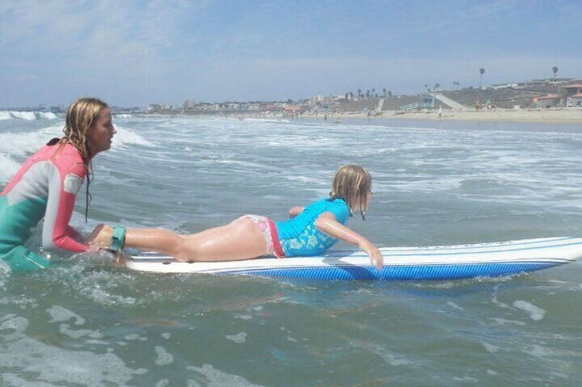 Instructor helps a girl catch the wave.