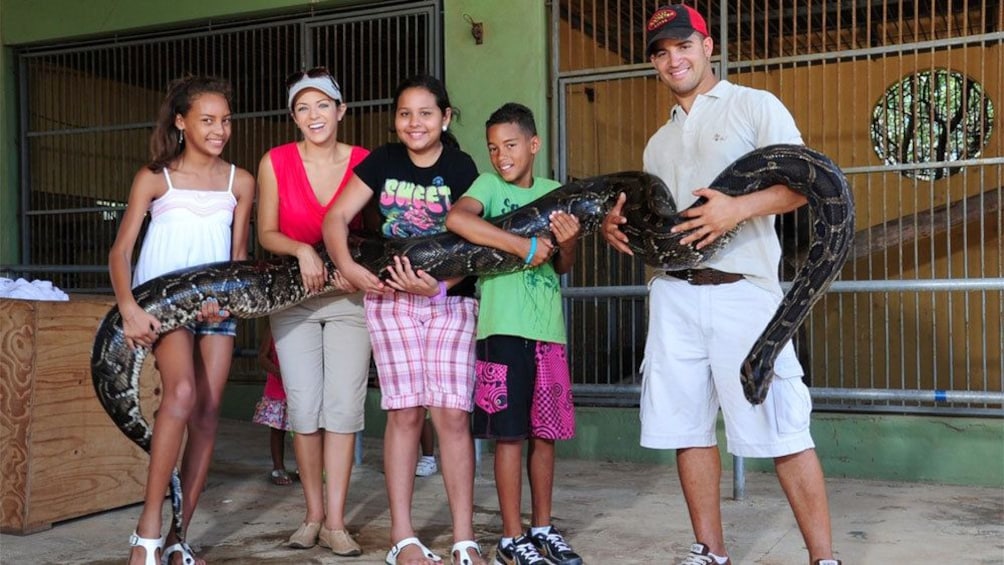Man with children holding a giant snake