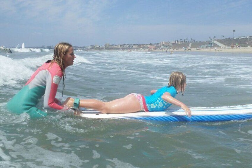 Instructor pushes girl into the wave. 