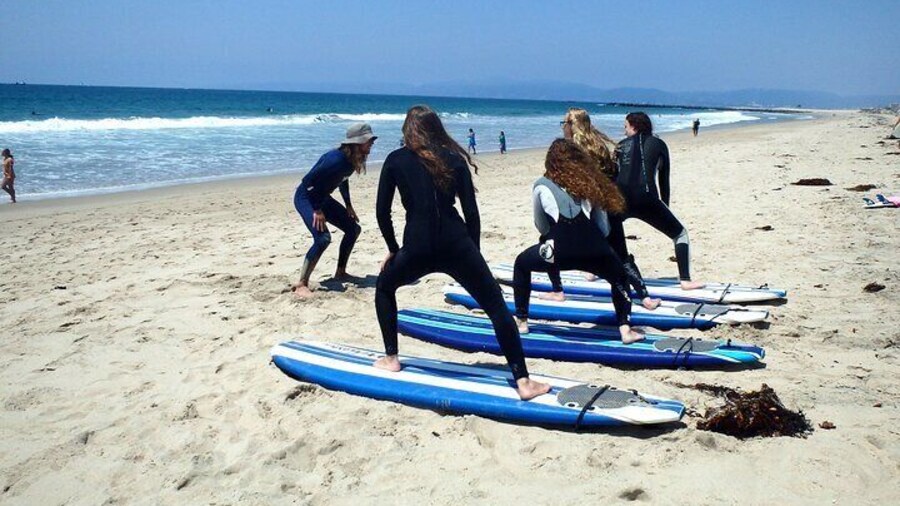 Group lesson practices their pop-up technique on the sand.