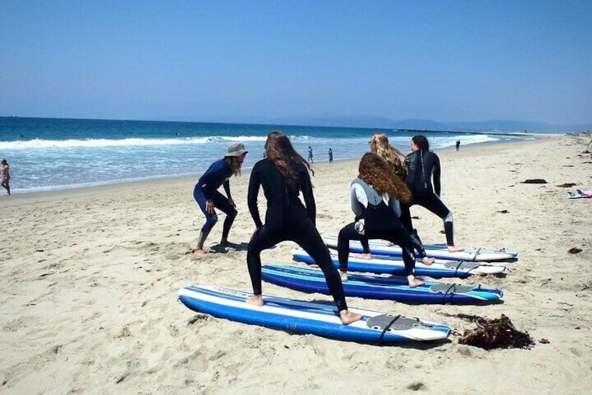 Group lesson practices their pop-up technique on the sand.