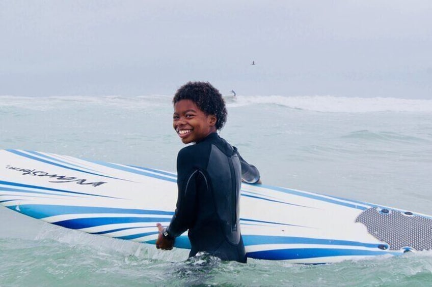 Boy smiles with his surfboard. 