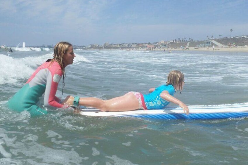 Instructor helps girl catch a wave. 