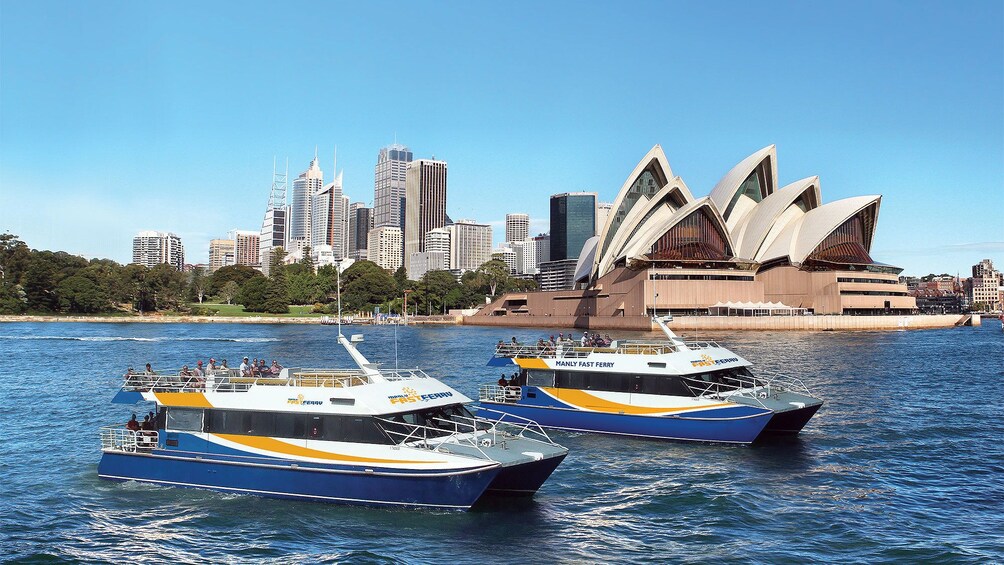 Two manly fast ferry boats in the water in front of the Sydney Opera House in Australia