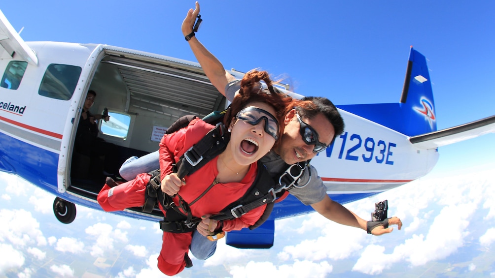 Show item 2 of 5. Woman skydiver with instructor jumping from plane over Atlanta