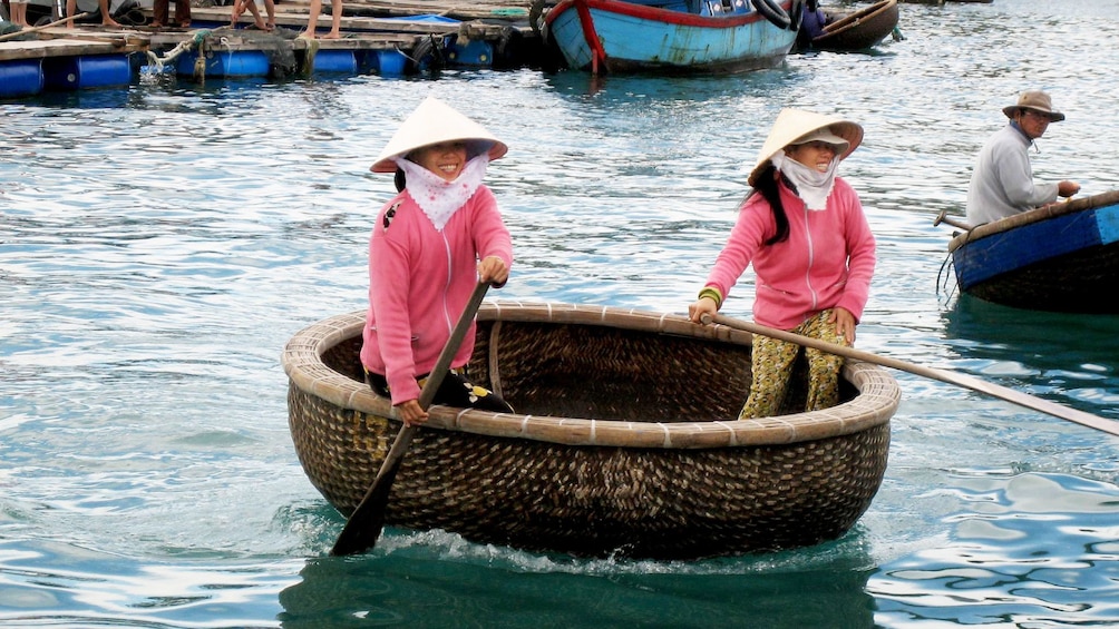 Two women paddling in basket boat in Hanoi