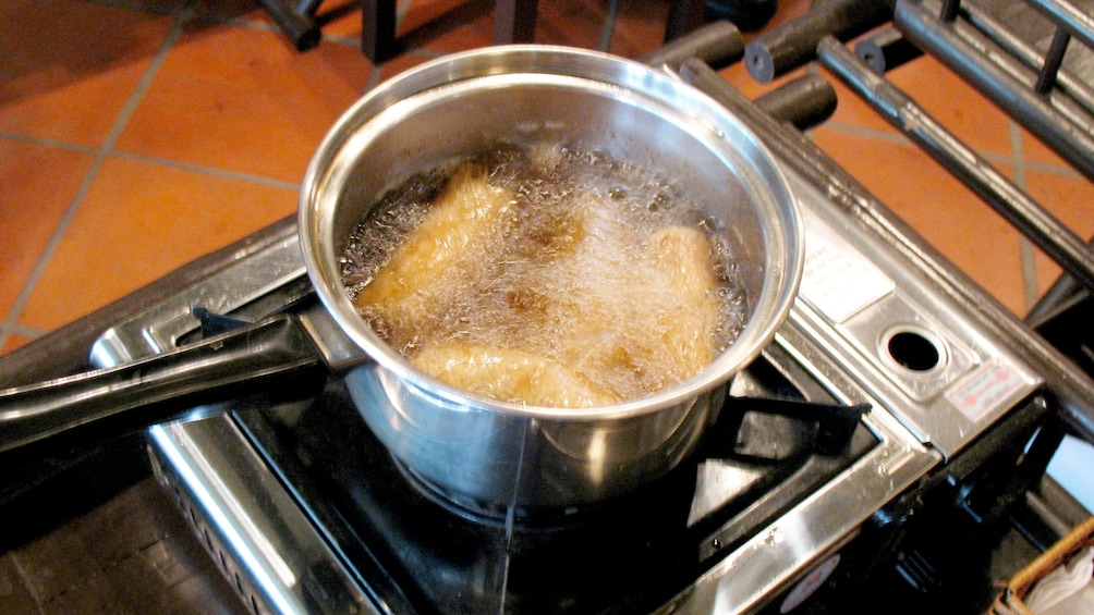 Food frying in oil on burner in kitchen in Hanoi