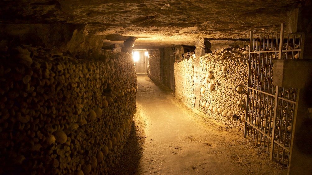 Entrance way into catacombs with bone lined walls in Paris