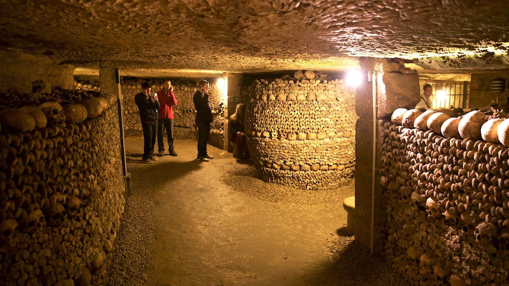 Tourists listening to audio guide on phones while in catacombs in Paris